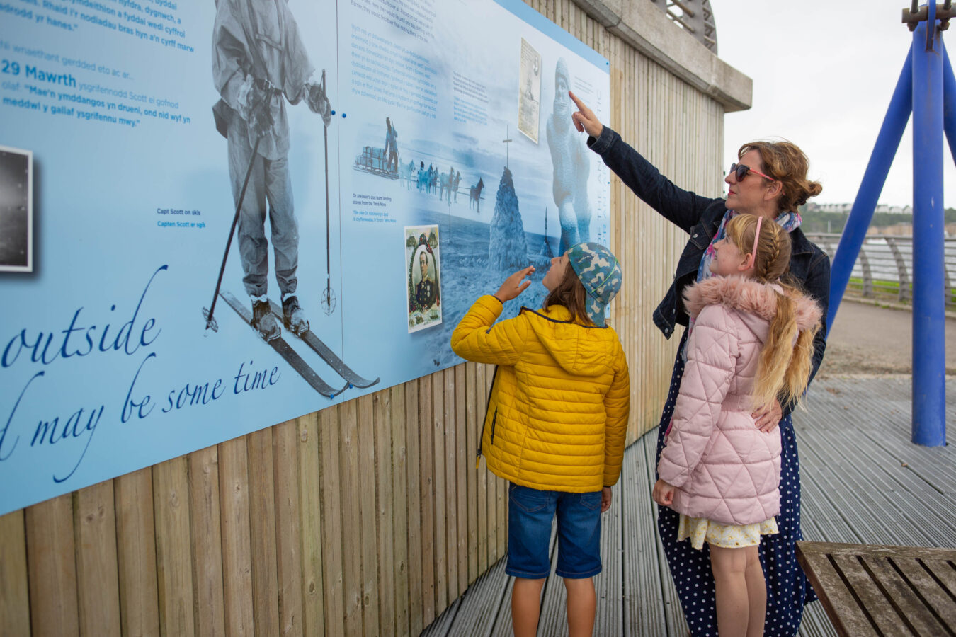 one adult and two children looking at a exhibition board.