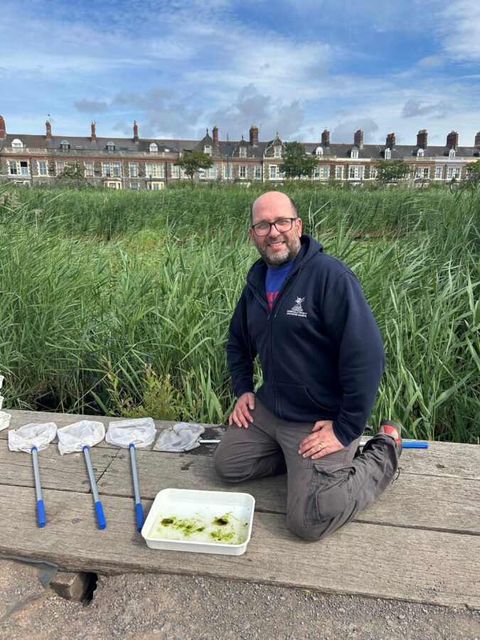 A person kneeling in the Wetlands.