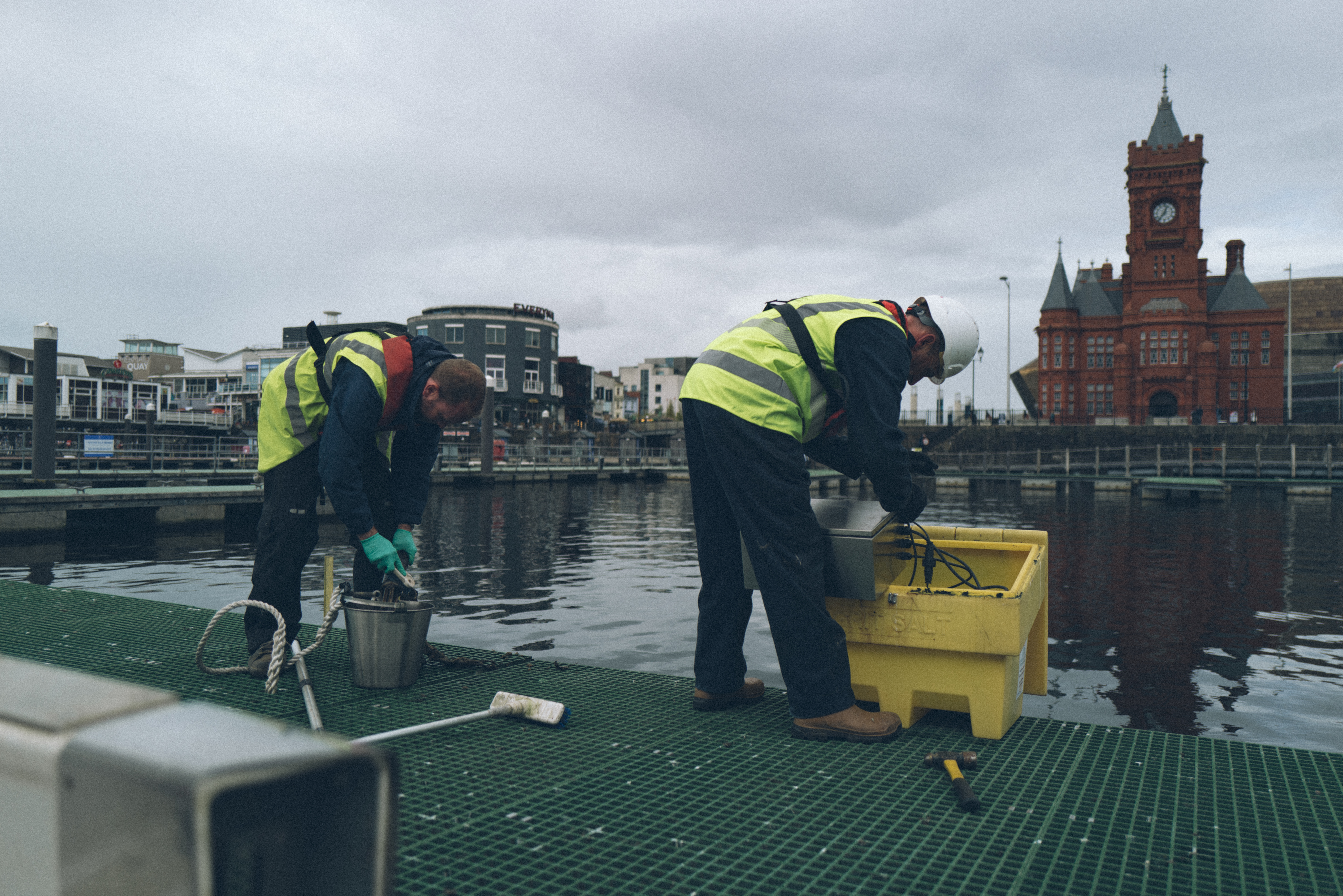 Two people in hi-vis near the water cleaning water quality instruments.