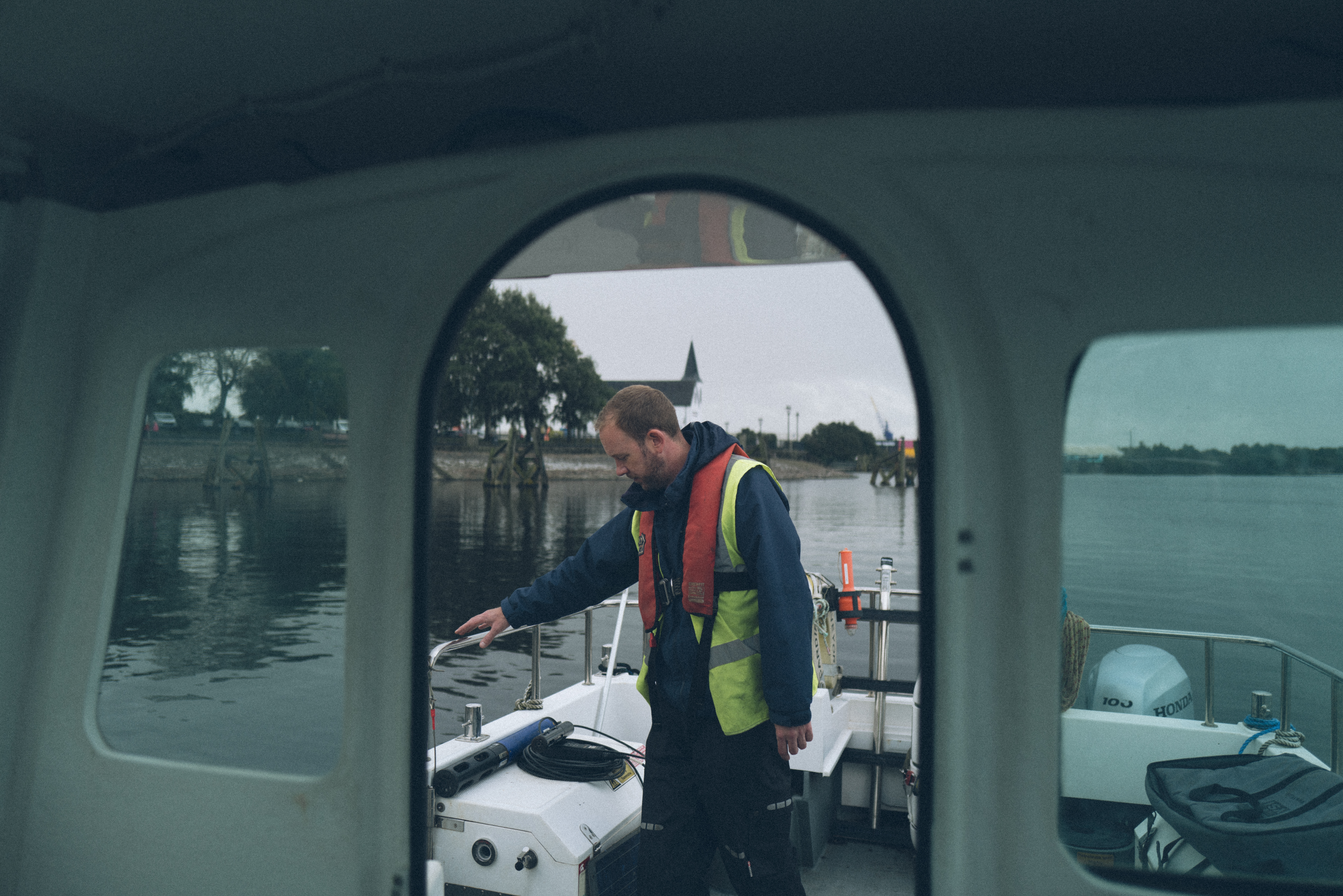 A person in hi-vis looking at the water from a boat,