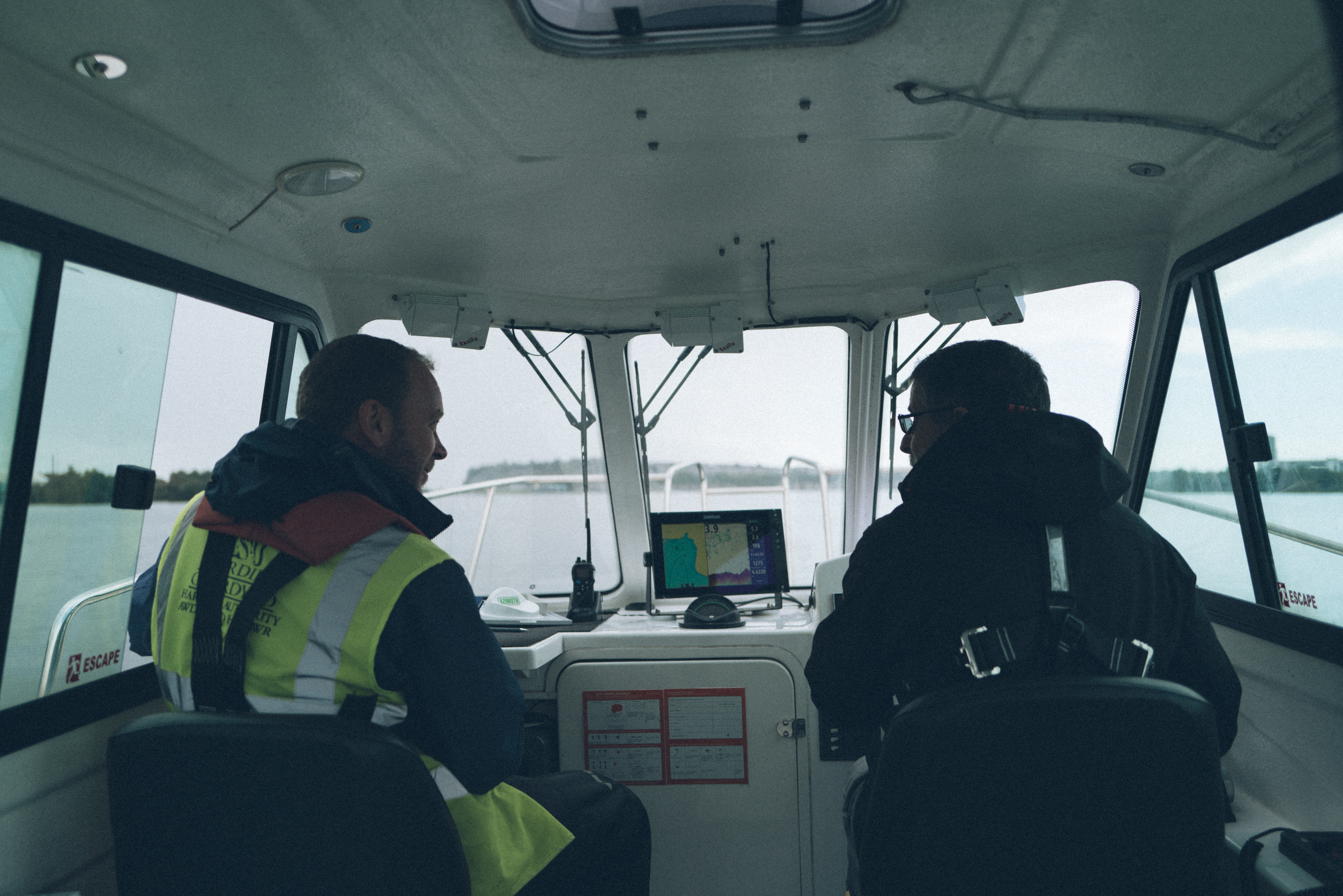 Two people, one driving boat the other sat next