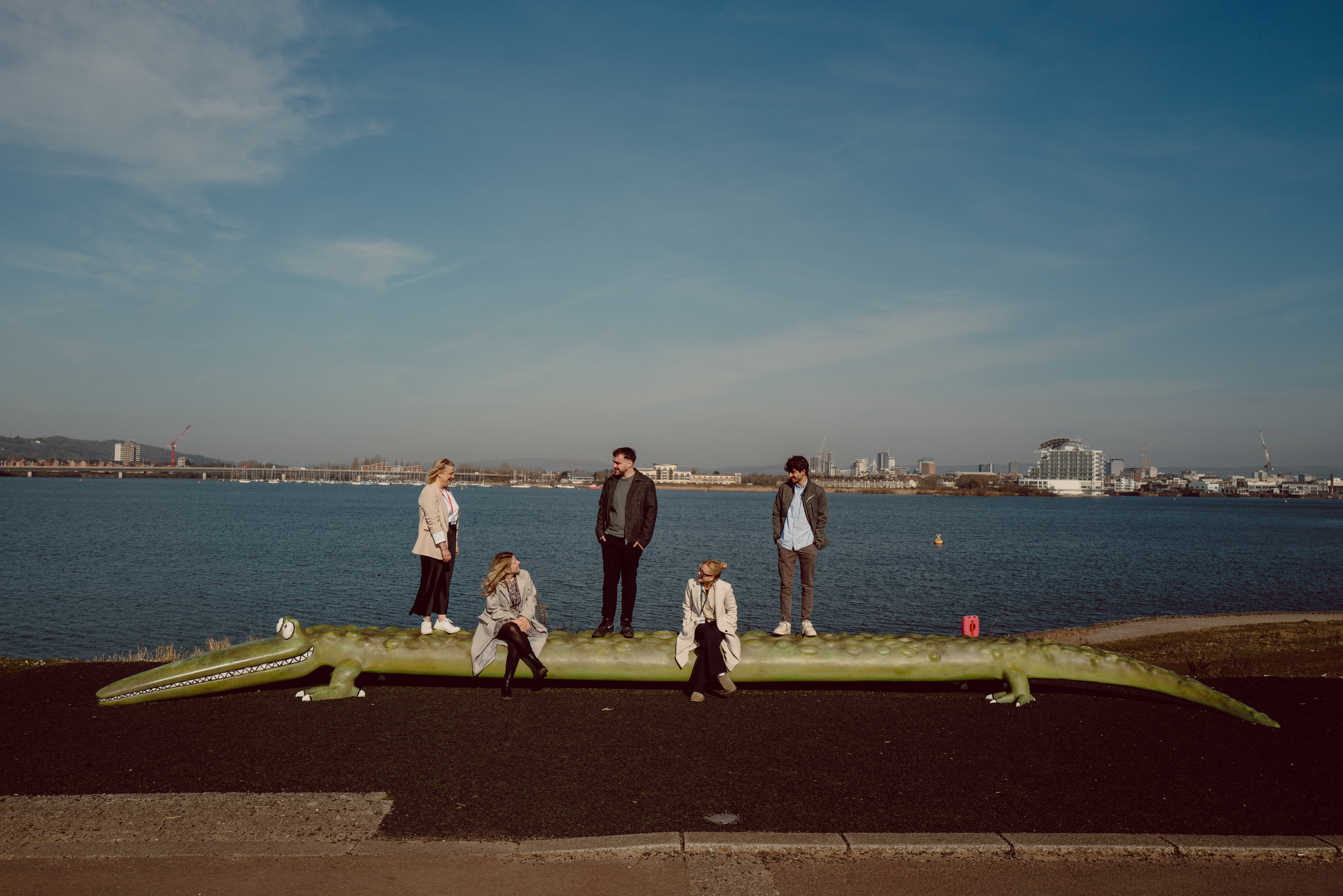 Five people on a crocodile sculpture.