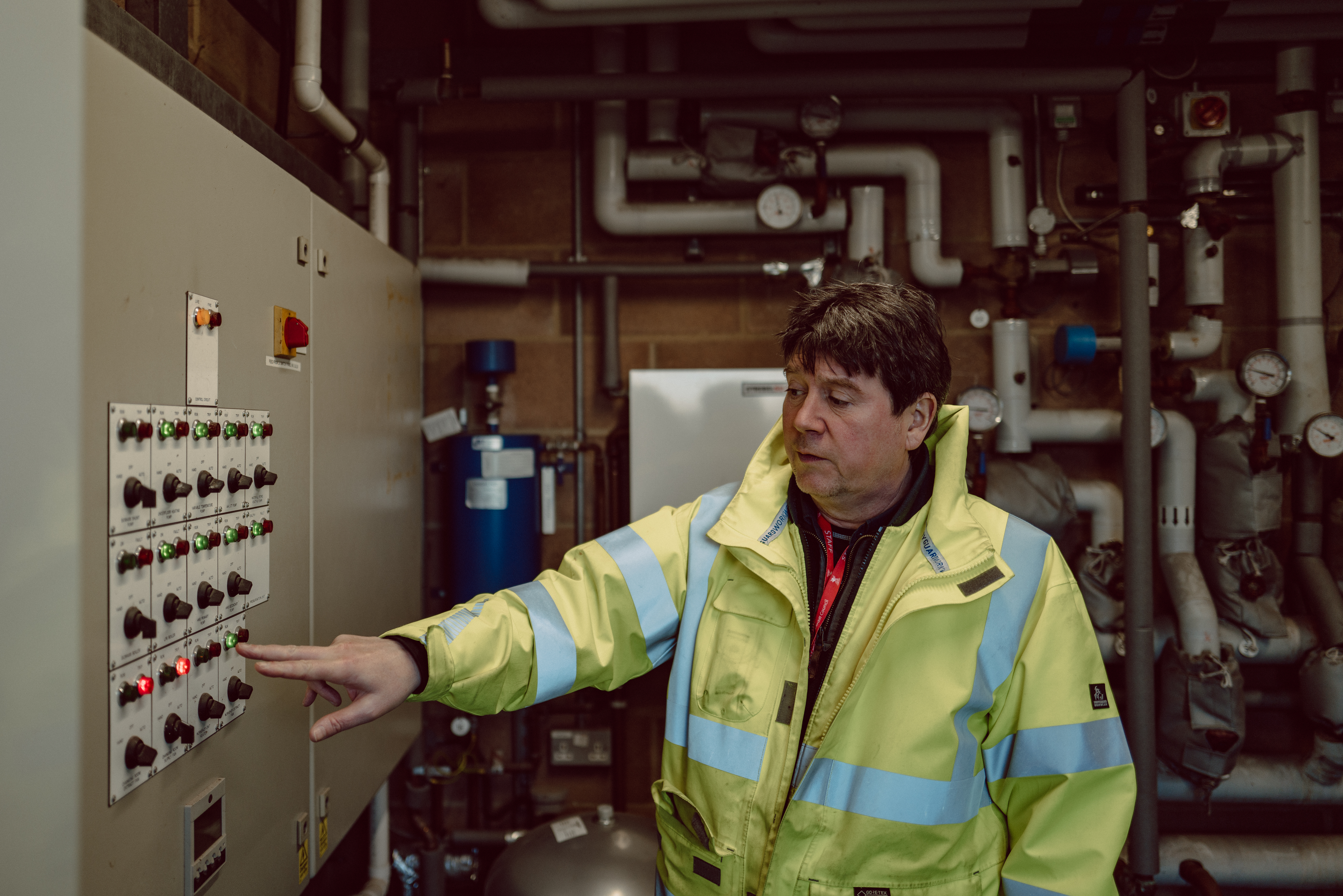 Person with hi-vis pointing at buttons on machine.