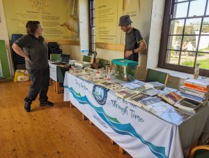 Two scientists in fieldwork clothing stood at a table talking